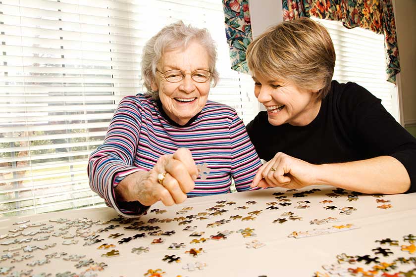 elderly woman and younger woman doing puzzle