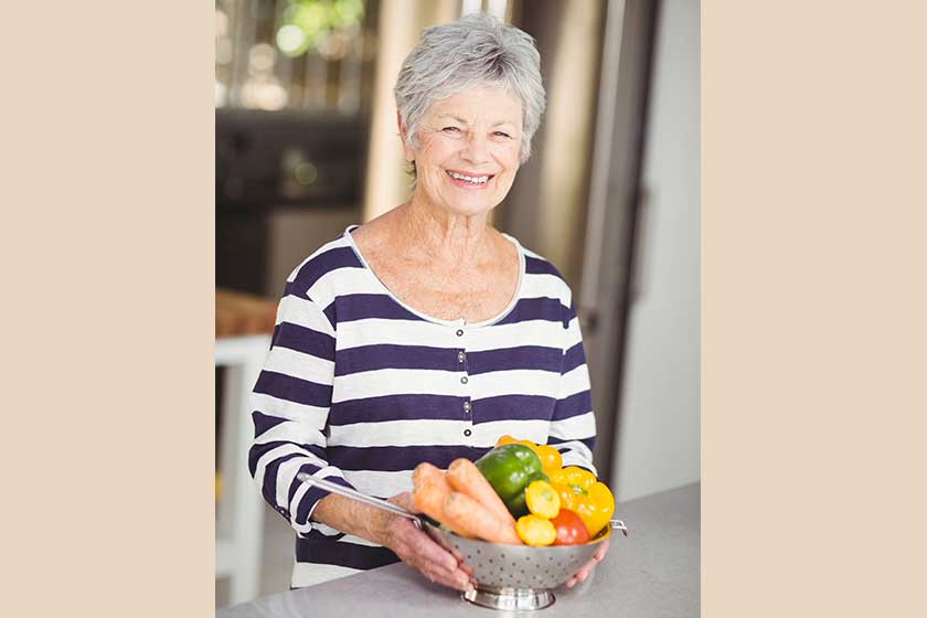 Woman holding colander with vegetables