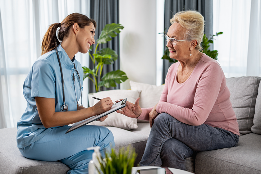 Female doctor supporting senior patient during home visit